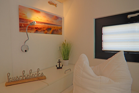 Cozy nook on a houseboat featuring pillows, decor items, window, wall art, and a reading lamp.