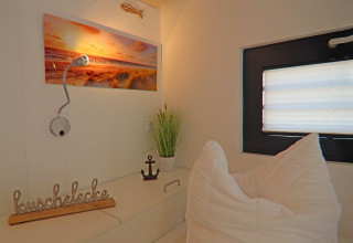 Cozy nook on a houseboat featuring pillows, decor items, window, wall art, and a reading lamp.