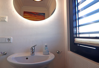 Bagno moderno su una houseboat con specchio illuminato, lavandino, finestra con persiane e sapone.