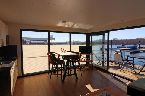 Living area of Houseboat Family & Friends with terrace and waterfront view in Germany, sunny and modern.