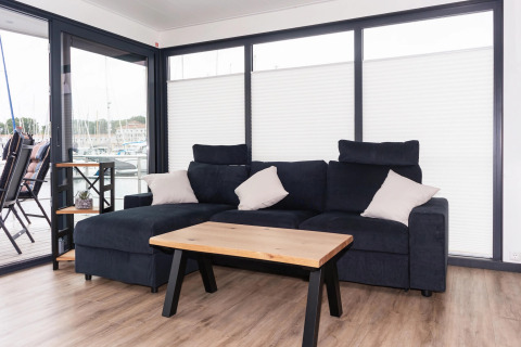 Living area on houseboat 'Family & Friends mit Hund LP 10' in Germany with sofa, table and large windows.