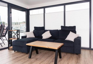Living area on houseboat 'Family & Friends mit Hund LP 10' in Germany with sofa, table and large windows.