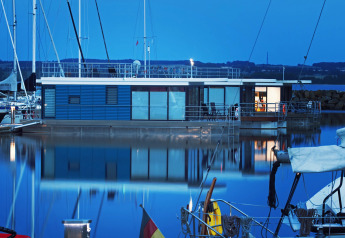 Moderne woonboot 'Family & Friends mit Hund LP 10' aangemeerd in een Duitse jachthaven bij valavond.