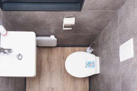 Modern toilet with wood floor and grey tiles, viewed from above, on the Family & Friends houseboat in Germany.