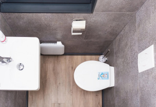 Modern toilet with wood floor and grey tiles, viewed from above, on the Family & Friends houseboat in Germany.