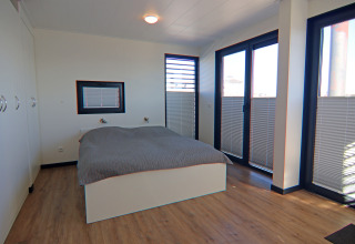 Bedroom on a houseboat with double bed, wooden floor, large windows, and cupboards at Family & Friends, Germany.
