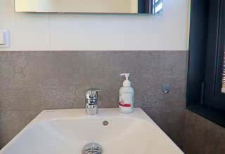 Modern washbasin with soap dispenser and chrome faucet in a houseboat bathroom in Germany.