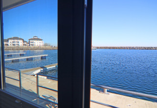 View from a houseboat window overlooking marina docks and apartments by the water in Germany.
