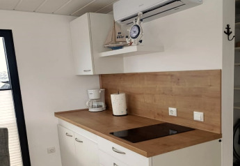 Moderne kitchenette op een woonboot met houten blad, inductiekookplaat, koffiezetapparaat en accessoires.