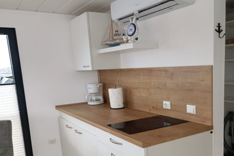 Coin cuisine moderne sur une péniche avec plan de travail en bois, plaque de cuisson et cafetière.