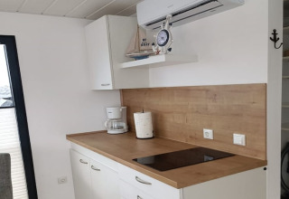 Coin cuisine moderne sur une péniche avec plan de travail en bois, plaque de cuisson et cafetière.