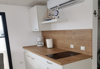 Modern kitchenette on a houseboat with wooden countertop, induction hob, coffee maker, and decor items.