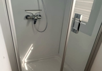 Modern shower stall with glass door and chrome handle on the Floating 44 houseboat in Germany.