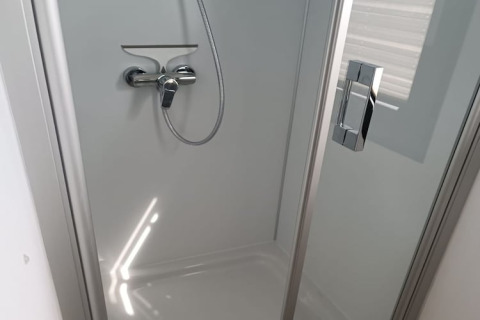 Moderna cabina doccia con porta in vetro e maniglia cromata sulla houseboat Floating 44 in Germania.