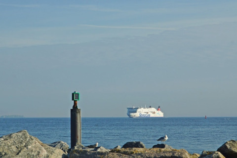 View from houseboat in Germany, looking at the Stena Line ferry, buoy in water, and seagulls on rocks.