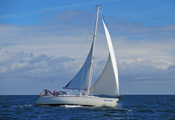 Sailboat gliding on the sea with blue sky and clouds, seen from Floating 44 - Boat 2 in Germany.