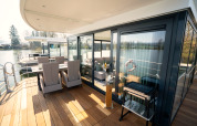 Buitenterras en eetruimte van een moderne woonboot in Höxter, met zicht op het rustige water.