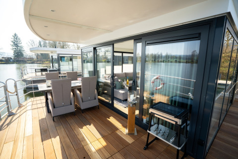 Udendørs spiseområde og terrasse på en moderne husbåd i Höxter, med udsigt over det rolige vand.