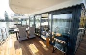 Zona pranzo esterna sul ponte di una moderna houseboat a Höxter, con vista sull’acqua tranquilla.