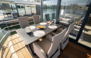 Coin repas extérieur sur une péniche à Höxter avec six chaises, table noire et vue sur la rivière.