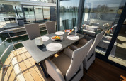Coin repas extérieur sur une péniche à Höxter avec six chaises, table noire et vue sur la rivière.
