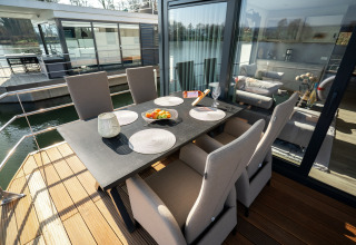 Buiten eetruimte op een woonboot in Höxter met zes stoelen, zwarte tafel en zicht op het water.