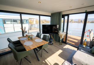 Modern living and dining area on a houseboat in Höxter with large windows overlooking the water.