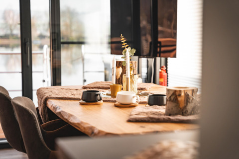 Mesa de comedor moderna con tazas de cerámica y decoración natural en una casa flotante en Höxter, Alemania.