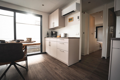 Cucina moderna e zona pranzo su una houseboat a Höxter con pavimenti in legno e grandi finestre luminose.
