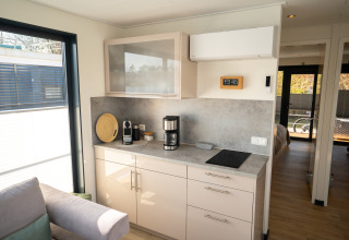 Angolo cottura moderno su Houseboat a Höxter con macchina da caffè, piano cottura e finestra luminosa.