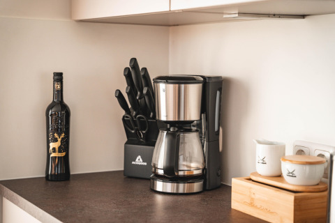 Modern kitchen counter on a houseboat in Höxter with coffee maker, knife set, wine bottle, and containers.