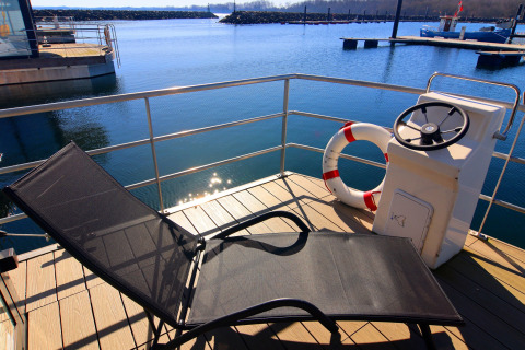 Sunny deck of Houseboat 'Family & Friends mit Hund LP 10' with lounge chair and life ring in Germany.
