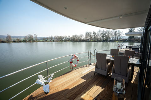 Buitenaanleg van een woonboot in Höxter met zicht op het water, eettafel en comfortabele stoelen.