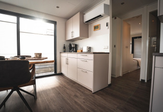Modern living room and kitchen on a houseboat in Höxter with dining table, large windows and wood flooring.
