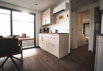 Salon et cuisine modernes sur une péniche à Höxter avec table à manger, grandes fenêtres et parquet.