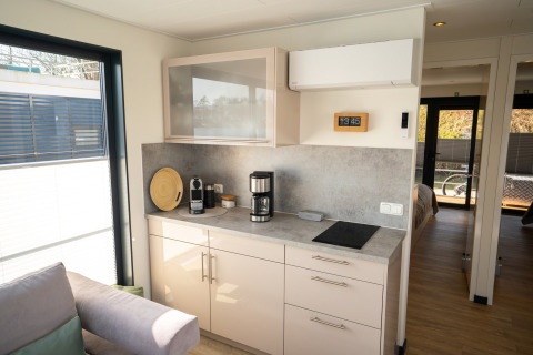 Modern kitchenette on a houseboat in Höxter, Germany, with coffee maker, stovetop, and wall clock.