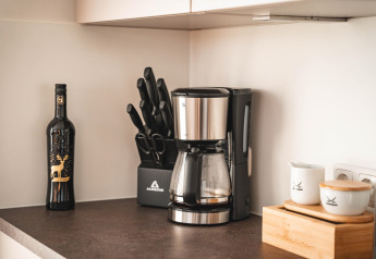 Moderne keukenhoek op een woonboot in Höxter, Duitsland, met koffiemachine, messenblok, wijn en potjes.