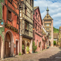 Malerische Kopfsteinpflasterstraße mit bunten Fachwerkhäusern in der Nähe von Corcieux, Grand Est, Frankreich.