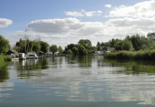 Uitzicht op een rustige rivier met woonboten en groene bomen vanaf Watercamper deluxe in Duitsland.