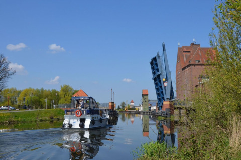Woonboot Watercamper deluxe vaart onder een openstaande brug op een zonnig kanaal in Duitsland.