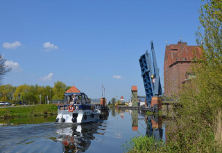 Woonboot Watercamper deluxe vaart onder een openstaande brug op een zonnig kanaal in Duitsland.