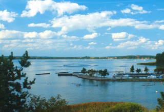 Uitzicht vanaf de woonboot 'Watercamper deluxe' in Duitsland met bomen, meer en blauwe lucht.