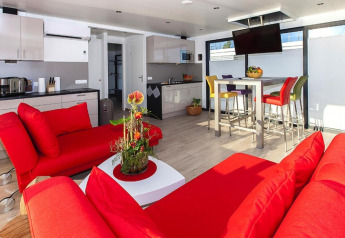 Modernes Hausboot mit roten Sofas, heller Küche und bunten Stühlen, Hausboot Blue Active in Deutschland.