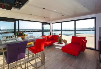 Casa flotante moderna con interior colorido, grandes ventanales y vistas al agua en Ribnitz-Damgarten, Alemania.