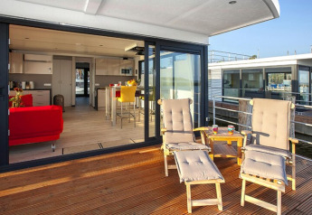 Sonnige Terrasse mit Liegestühlen und modernem Interieur im Hausboot «Floating Houses Blue Active» in Deutschland.
