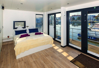 Chambre sur une péniche avec grandes fenêtres et vue sur le port à Ribnitz-Damgarten, Allemagne.