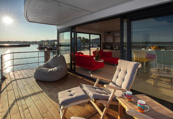 Sonnige Terrasse auf Hausboot Floating Houses Blue Active mit Lounge, Seeblick und gemütlicher Sitzecke.
