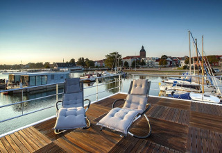 Dos tumbonas en la cubierta de una casa flotante con vistas al puerto de Ribnitz-Damgarten, Alemania.
