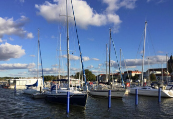Boote und Hausboote im Yachthafen von Ribnitz-Damgarten, unter blauem Himmel in Deutschland.
