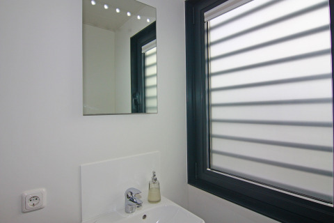 Modernes Badezimmer mit Spiegel, Waschbecken, Seifenspender und großem Fenster in einem Hausboot.